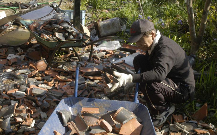A man clears roof-tiles dislodged by an earthquake near Kumamoto, Japan on Tuesday.  The region was hit by a 6.5 magnitude quake on April 14, then with a 7.3 quake less than 24 hours later. 

