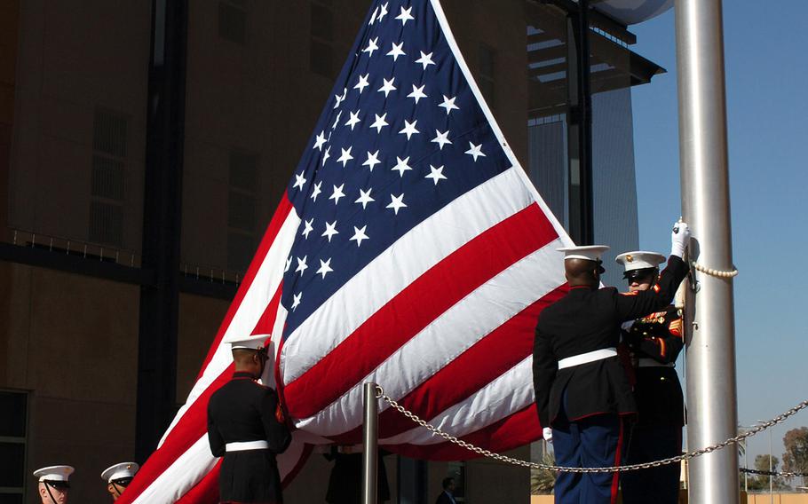 In a 2009 file photo, Marines of the Marine Security Detachment of the U.S. Embassy Baghdad, Iraq raise the flag at the new Embassy's dedication ceremony.
