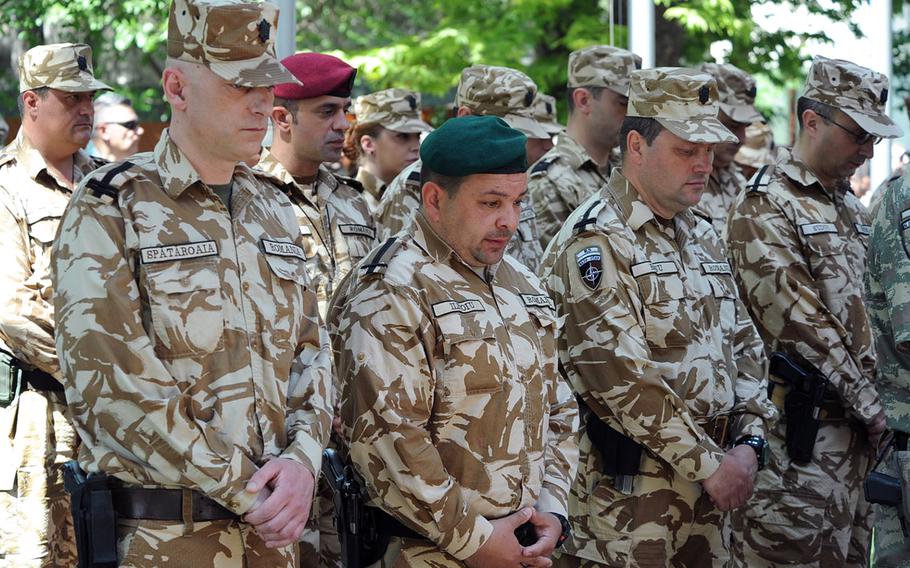 Romanian soldiers bow their heads during a memorial service for Romanian army Sgt.1st Class Iulian Dumitrescu and Sgt. Adrian Vizireanu at Resolute Support headquarters in Kabul, Afghanistan, Monday, May 9, 2016.The two were killed Saturday in an insider attack. A third soldier was wounded. Romania's defense minister Mihnea Motoc says three Afghans have been arrested in connection with the attack.