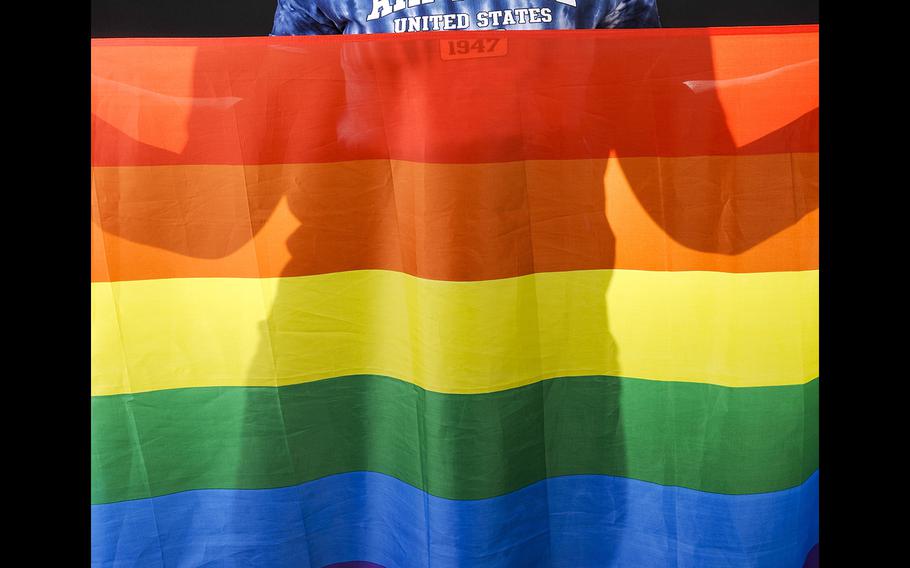 A U.S. airman holds a rainbow flag for Lesbian, Gay, Bisexual, and Transgender Pride Month during a June 12, 2014, event at Eielson Air Force Base, Alaska. 