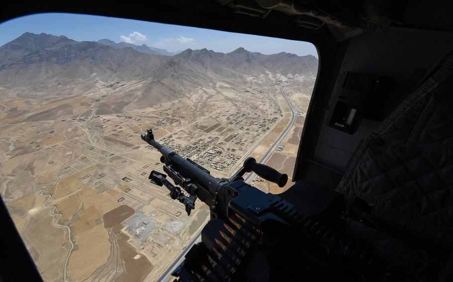 An M2 .50-caliber machine gun sticks out of a window of an American CH-47 Chinook helictopter as it flies north of Kabul, Afghanistan, on Tuesday, July 12, 2016.