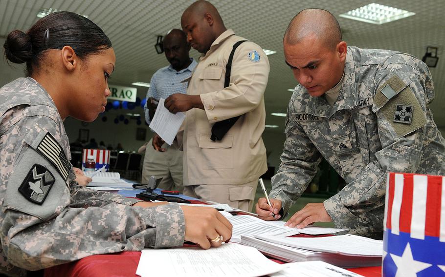 U.S. Army Pfc. Chyna Williams, from Crestview, Fla., assists Sgt. Charles Rodriguez, from Chicago, Ill., complete an absentee ballot at Camp As Sayliyah, Qatar, Oct. 16, 2008.