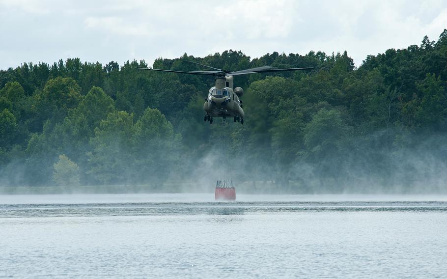 A U.S. Army CH-47 Chinook helicopter hovers while filling a bucket, suspended from the helicopter, during wildfire operations training at Lake Kyle Recreation Area, Fort Campbell, Ky., on Aug. 20, 2013.