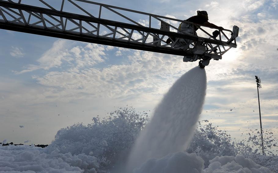 A civilian firefighter with the 436th Civil Engineer Squadron Fire Department works the nozzle of a ladder truck hose to spray foam on Sept. 16, 2013, at Dover Air Force Base, Del.