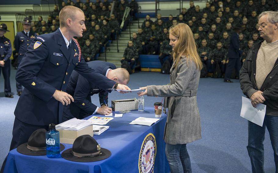 Petty Officer 1st Class Edward Burke, ceremonial director at Coast Guard Training Center Cape May, N.J., hands paperwork to Kayla Ellis, a resident of New Gretna, N.J., as she checks in to the annual Thanksgiving Operation Fireside event, Thursday, Nov. 24, 2016. Operation Fireside has been organized by the American Red Cross Southern Shore Chapter and the Coast Guard Training Center since 1981 and places recruits in host family homes during both Thanksgiving and Christmas.