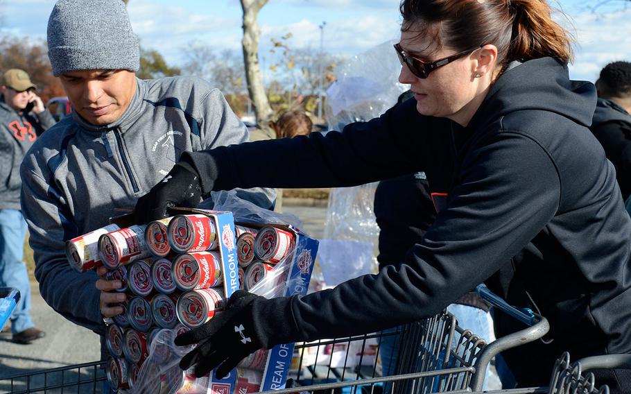 U.S. Air Force Master Sgt. Dathan Hayes, 633rd Communications Squadron first sergeant, and Jennifer May, wife of Master Sgt. Philip May, 633rd Medical Group first sergeant, unwrap canned goods during Operation Warmheart at Joint Base Langley-Eustis in Virginia on Nov. 20, 2016. The Langley First Sergeant Council hosts the Operation Warmheart Thanksgiving basket drive annually to gather food for JBLE service members and their families.