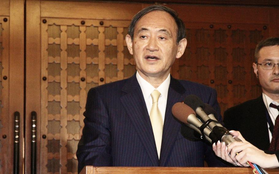 Japan's Chief Cabinet Secretary Yoshihide Suga speaks Thursday at Nago's Bankoku Shinryokan Hall. Suga criticized Okinawa Gov. Takeshi Onaga for boycotting the event, which saw the U.S. return 4,000 of the Northern Training Area's 7,542 hectares to the Japanese government.