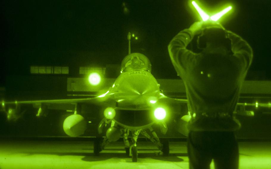 U.S. Air Force Staff Sgt. Chris Heising, a crew chief at the 162nd Wing, uses wands to marshal an F-16 after night training in Tucson, Arizona, February 24, 2016. 