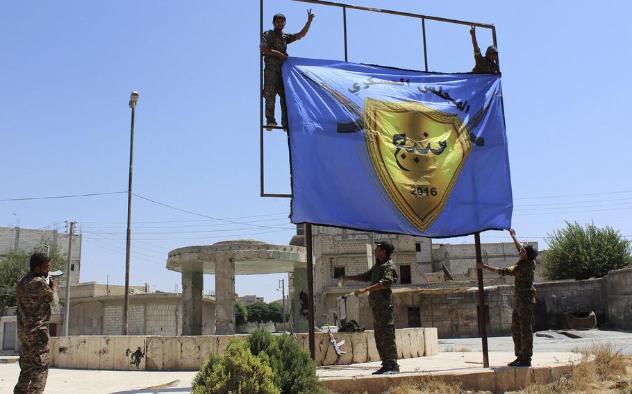 This file photo released on Aug. 8, 2016 by Hawar news, the news agency for the semi-autonomous Kurdish areas in Syria (ANHA), shows Kurdish-led Syria Democratic Forces raising their flag after driving Islamic State militants out of the area, in Manbij, Syria.