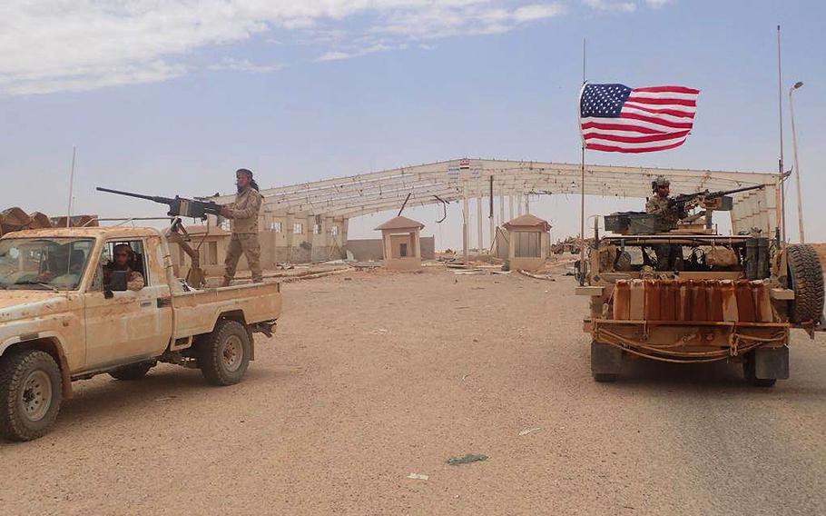 A U.S.-backed anti-government Syrian fighter form Maghaweer al-Thawra stands on a vehicle with heavy automatic machine gun, left, next of an American soldier, also standing on an armored vehicle, as they take their position at the Syrian-Iraqi crossing border point of Tanf, south Syria, on Tuesday, May 23, 2017.