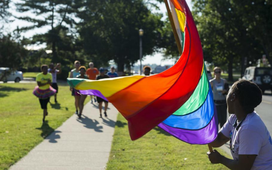Senior Airman Kiana Brothers waves the pride flag during a Pride Month run at Scott Air Force Base, Ill., June 24, 2016. The Vicenza military community in Italy will hosting its first-ever LGBT pride event on June 7, 2017.