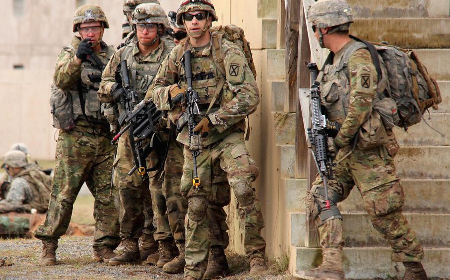 Soldiers with the 10th Mountain Division maneuver along a wall while conducting live-fire training at Fort Polk, La., on Jan. 21, 2017.