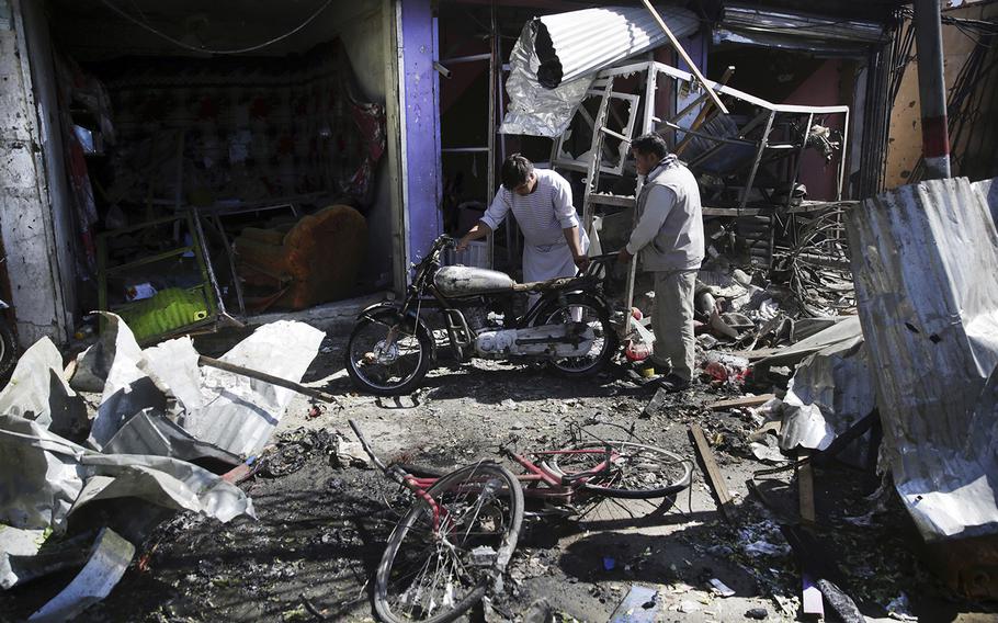Men look at the remains of their properties at the site of a suicide attack in Kabul, Afghanistan, Monday, July 24, 2017. The Taliban claimed responsibility for the Monday attack and launched another attack on an Afghan military base in southern Kandahar province on Tuesday.