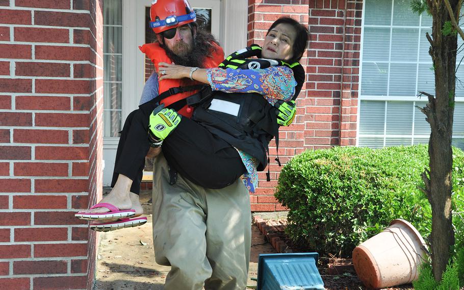 Team Rubicon volunteer Stephen Reid carries Van Ngo back to the boat from her flooded home in Beaumont, Texas after he and his team helped her retrieve medication and clothing items on Sept. 2, 2017. The non-profit veterans organization utilizes veterans skills to respond to disasters.