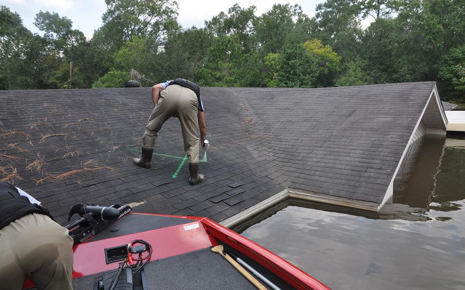 Team Rubicon volunteer Anthony DiToma marks a house in a flooded neighborhood of Beaumont, Texas as checked after the team’s search and rescue boat pounded the roof to make sure no one was trapped inside on Sept. 2, 2017. The water was still up to rooftops but had started to recede.
