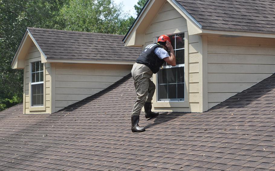 After climbing from his boat onto the roof, Team Rubicon volunteer Anthony DiToma checks to make sure no one is in a flooded house in Beaumont, Texas on Sept. 2, 2017. The water was still up to rooftops but had started to recede.