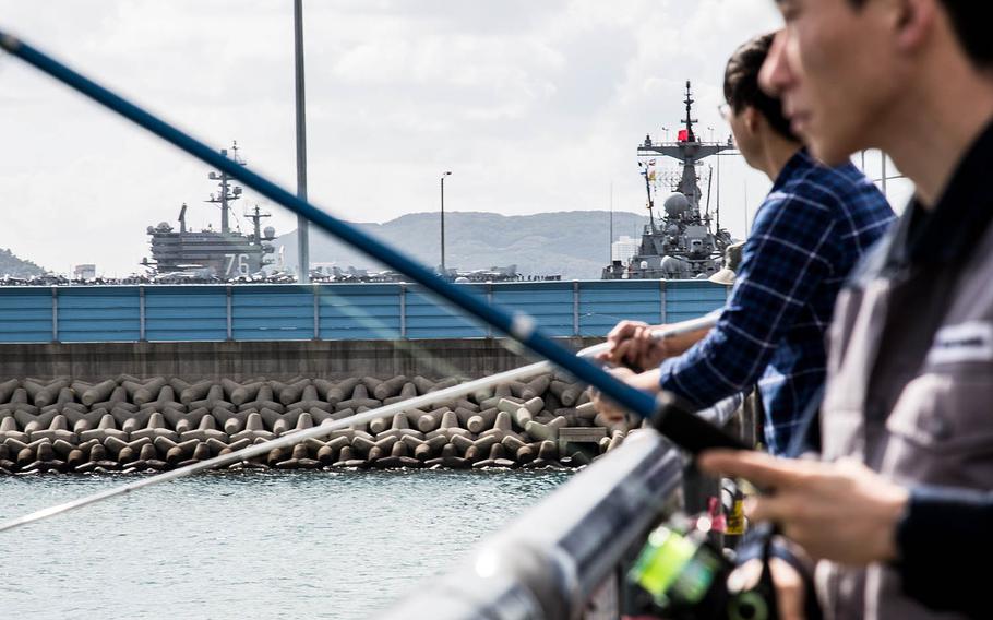 Locals fish near the USS Ronald Reagan at Busan, South Korea, Saturday, Oct. 21, 2017.