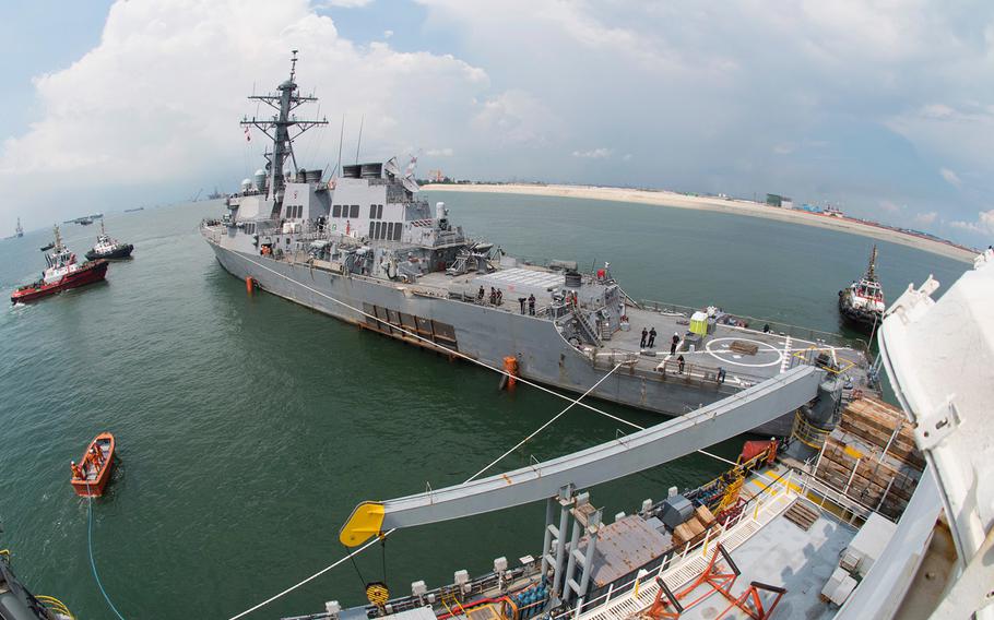 The Arleigh Burke-class guided missile destroyer USS John S. McCain is towed out to sea to meet the heavy lift transport vessel MV Treasure, Oct. 6, 2017.