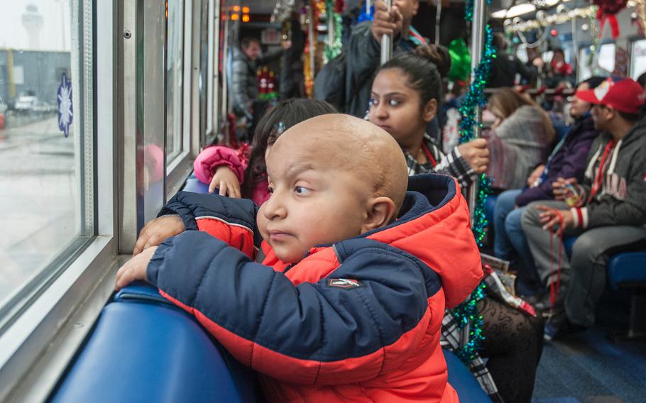 Abdulah Iftikhar, 7, a children's hospital patient, looks out the window of a shuttle bus taking passengers from a United Airlines' Fantasy Flight to the "North Pole"back to the main terminal at Washington-Dulles International Airport in Virginia on Saturday, Dec. 9, 2017, 
