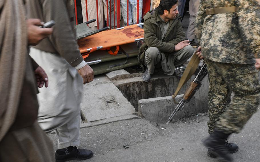 An Afghan man waits, smoking, beside a pile of stretchers outside Emergency hospital in Kabul, Afghanistan, on Saturday, Jan. 27, 2018, following a ambulance-borne bomb blast earlier in the day in a busy part of town. The attack left dozens dead and more than 150 wounded.