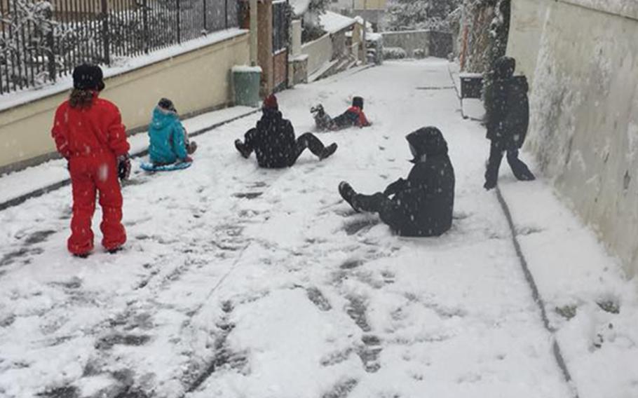 American children sled down snow-covered streets Tuesday, Feb. 27, 2018, near Naples, Italy. A snowstorm closed the naval base schools for the day.