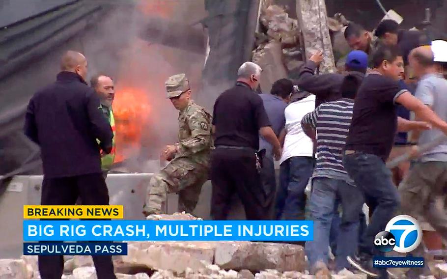 Bystanders rush to rescue people trapped in wreckage as flames break out after a big rig gravel hauler and cars collided on southbound Interstate 405 near the Mulholland Bridge on the west side of Los Angeles, Monday, April 30, 2018.