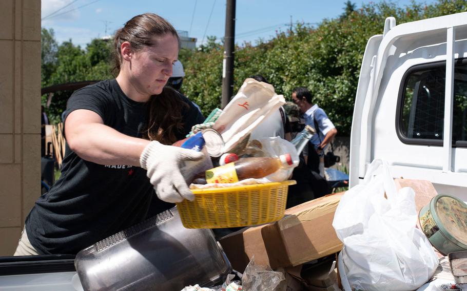 Cpl. Carlye Rehmann, an accident investigator with the provost marshal at Marine Corps Air Station Iwakuni, loads water-logged items into the back of a truck for disposal in the Shuto area of Iwakuni, Japan, on July 12, 2018.