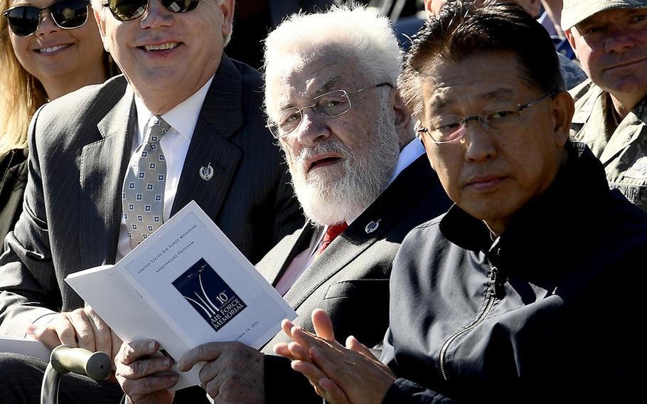 Adrian Cronauer, center, references the event program during the Air Force Memorial's 10th anniversary ceremony in Arlington, Va., Oct. 14, 2016.