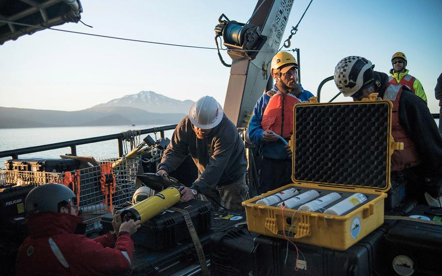 Project Recover members Bob Hess, Brian Kim, and Matt Breece test an acoustic transponder, which was used during a seafloor search to find World War II wreckage in the Aleutian Islands.