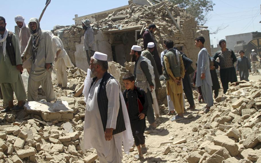 Afghan men stand near a damaged house following a Taliban attack in Ghazni, Afghanistan, Wednesday, Aug. 15, 2018. A Taliban assault on two adjacent checkpoints in northern Afghanistan killed at least 30 soldiers and police, officials said Wednesday.