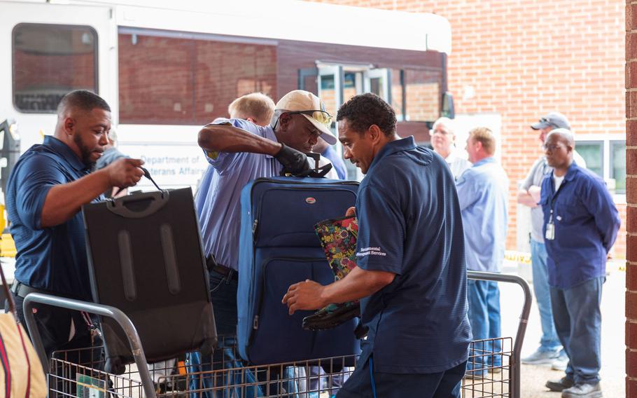 Workers help unload luggage for patients evacuated from Hampton VA Medical Center to Richmond VA Medical Center in Virginia on Wednesday, Sept. 12, 2018.