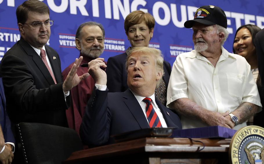 President Donald Trump hands a pen to Veterans Affairs Secretary Robert Wilkie during a spending bill signing ceremony at VA Southern Nevada Healthcare System, Friday, Sept. 21, 2018, in Las Vegas.