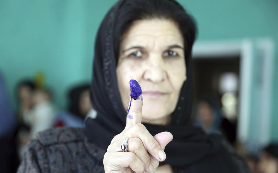 An Afghan woman shows her inked finger after casting her vote at a polling station during the Parliamentary elections in Kabul, Afghanistan, Saturday, Oct. 20, 2018.