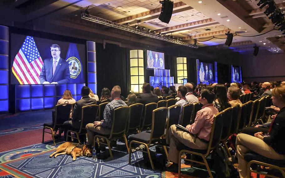 Attendees at the Student Veterans of America National Convention in Orlando, Fla., watch as Secretary of Veterans Affairs Robert Wilkie addresses them by a remote feed. Wilkie was to have attended in person, but canceled earlier in the week due to the partial government shutdown, the VA said.