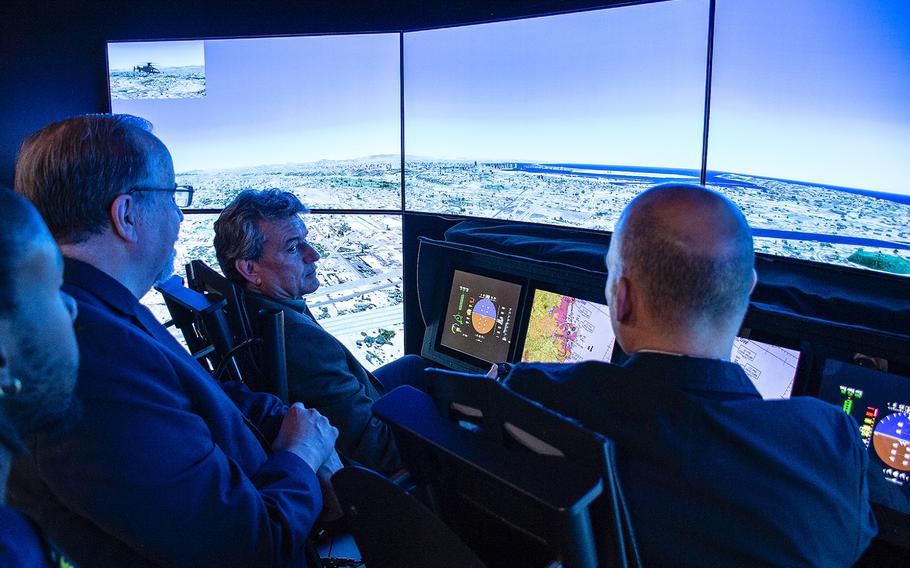 A small crowd of men gather at the annual AUSA convention in Washington, D.C., on Tuesday, Oct. 15, 2019, to watch a participant in a cockpit simulator try to safely land a Sikorsky-Boeing SB-1 Defiant compound helicopter.