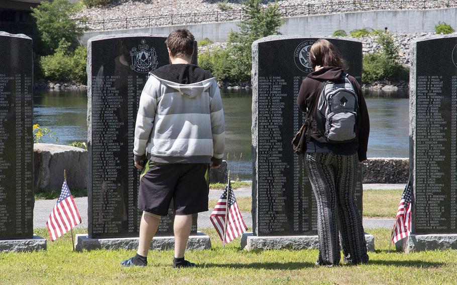 Visitors to the Veterans Memorial Park in Lewiston, Maine, in August, 2019, read the names on stones listing local veterans.