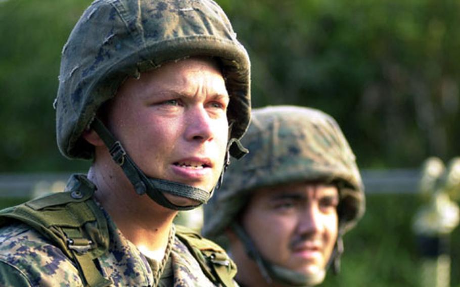 Cpl. Erik Reuter, 26, an armory custodian from Fort Lauderdale, Fla., and Cpl. Saul Solis, 22, a comptroller from Pampa, Texas, both with Marine Air Control Group 18, shout encouragement Friday to other Marines crossing one of the rope bridges on the endurance course.