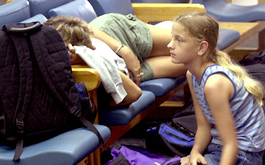 Stormy Hollandsworth, 10, and her mother, Sherry Hurst-Perry, wait at Guam’s Andersen Air Force Base for a space-available flight Sunday from Guam to California, where they planned to continue to Ohio to visit family while Guam recovers from typhoon damage.