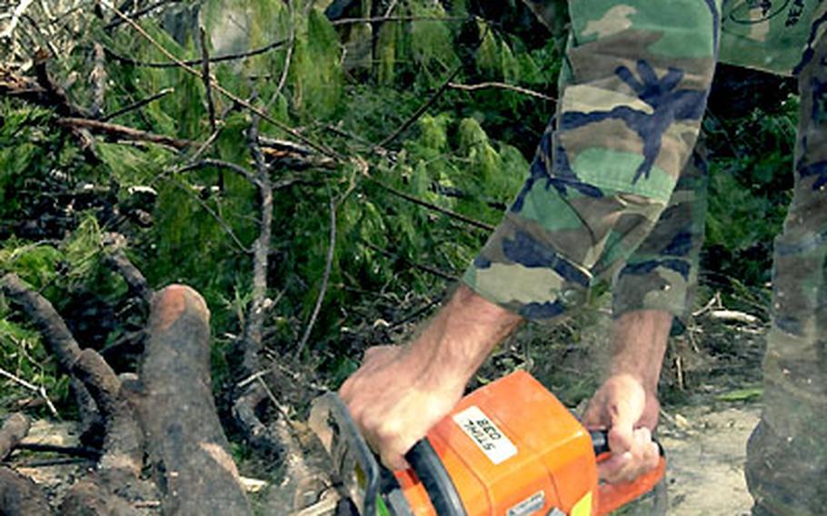 Constructionman Richard McLean, from Naval Mobile Construction Battalion 74, chops fallen trees on Guam.