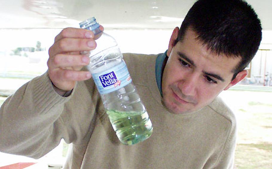 Flight Instructor Julio Suitt checks to see if the fuel in a Cessna 120 is free of sendiment ...