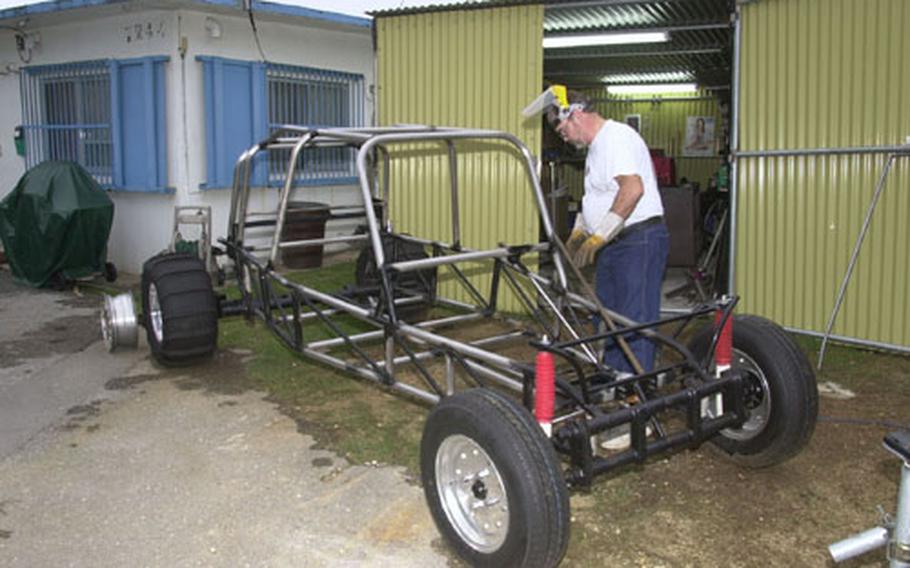 Kurt Lusso, a civilian contractor on Kadena Air Base, attaches a specially-fit tube onto the frame of a dune buggy, one of two off-road vehicles he's building in his spare time.