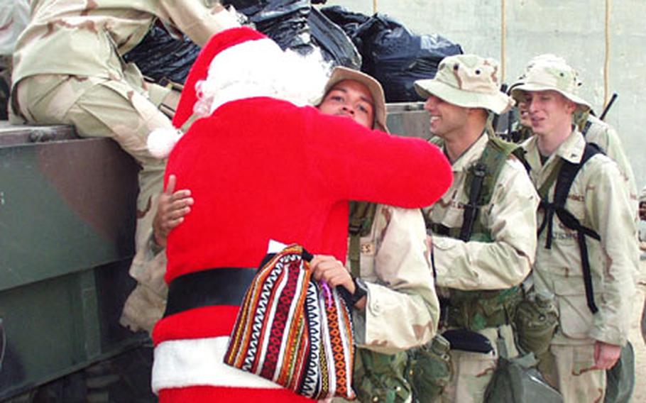 Marine Corp. Ted Lachance hugs Santa Claus, played by Maj. Mike Riddle. Members of the I Marine Expeditionary Force in Kuwait received gifts donated by an American couple's program called Operation Christmas Basket.