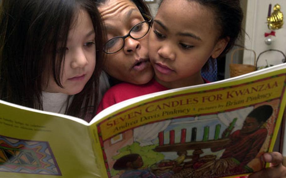 D'Juana Cephus (center) reads a book about Kwanzaa on Friday with her 8-year-old daughter, Raquel, right, and Raquel's friend, Azlyn Heidt, also 8, at Cephus' home in the Sagamihara Housing Area near Camp Zama, Japan.