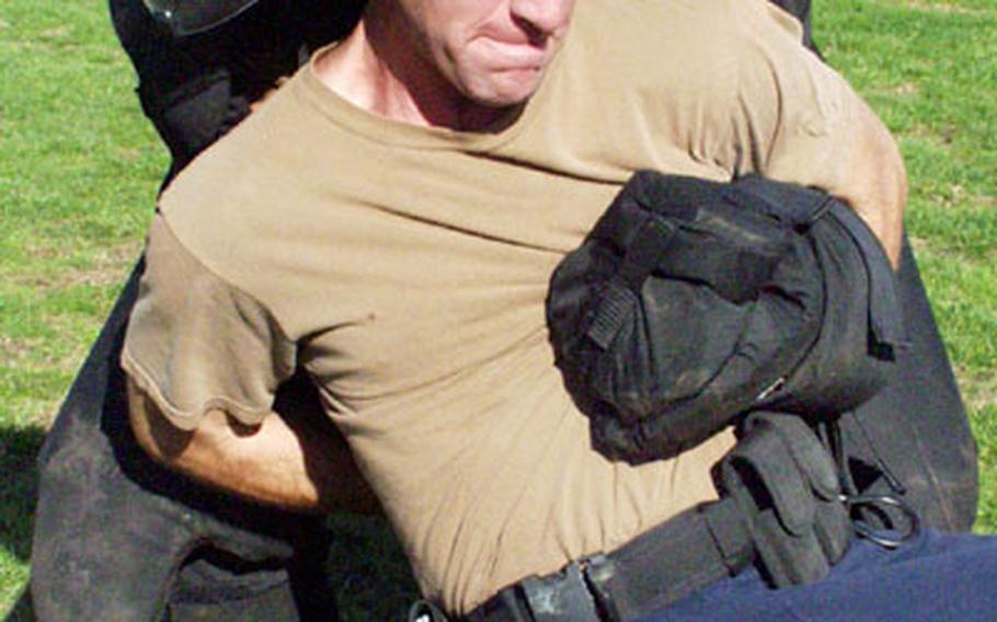 Petty Officer 3rd Class Paul Kuntz tries to keep his plastic gun from an “attacker” in a padded suit as part of a training exercise at Naval Station Rota, Spain.