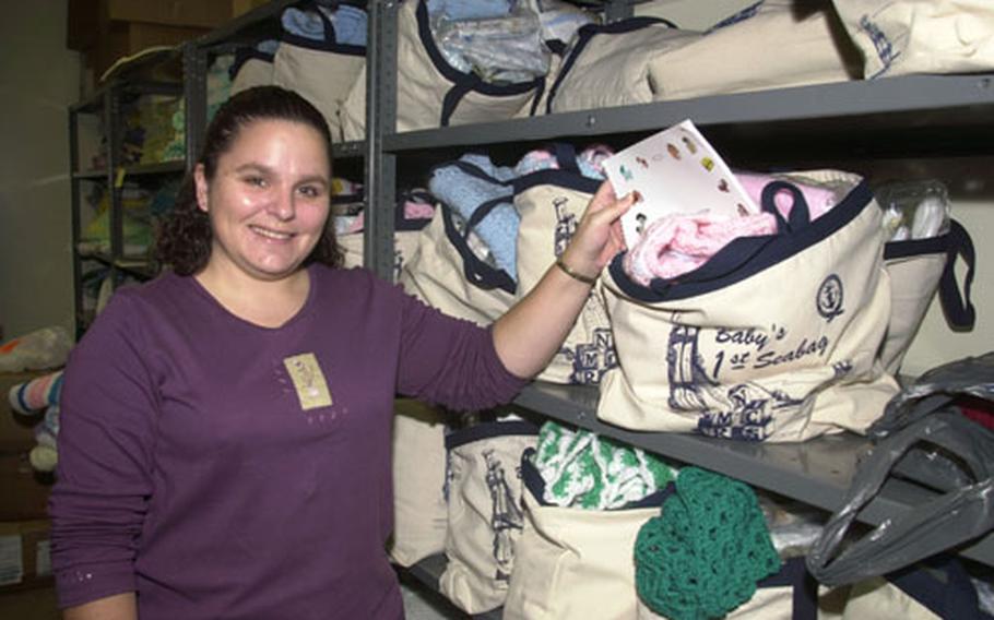 Tamara Dickerson, volunteer of the quarter for the Navy Marine Corps Relief Society on Okinawa, shows off a Baby's First Seabag, a gift they give to parents who attend the Budget For Babies class.