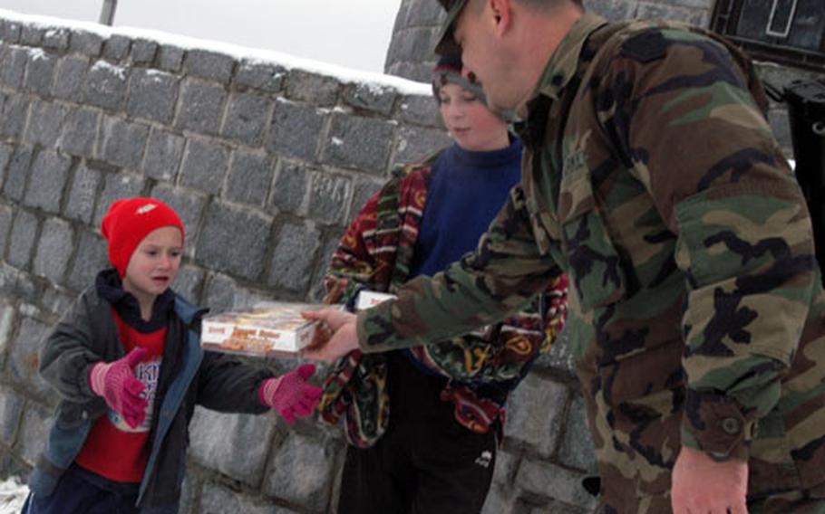 Spc. Kevin Bubb of C Company, 1st Battalion, 109th Infantry Regiment gives peanut butter cracker sandwiches to two Bosnian boys during a patrol through eastern Bosnia on New Year's Day. The boys turned in some rusty bullets to the soldiers.