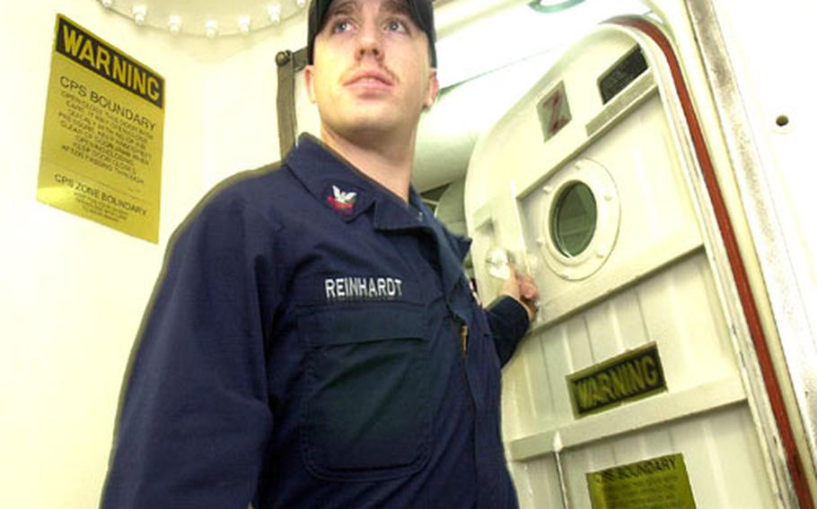 Petty Officer 2nd Class Michael Reinhardt, a sailor aboard the USS John S. McCain, enters one of the ship's airlocks.