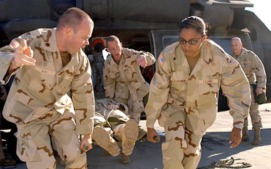 Maj. Arno Kivi, left, and Spc. Xiomara Gardner, right, from the 865th Combat Support Hospital, unload a simulated casuality from a Black Hawk helicopter during a medical evacuation training exercise on Camp Doha, Kuwait. The hospital will operate a Level 3 medical treatment facility at Kuwait Armed Forces Hospital.
