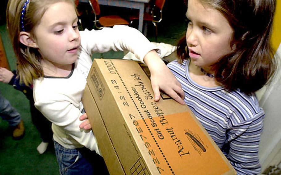 Allison Couch, left, and Melissa Patten lug boxes of Girl Scout cookies into the group's building at Atsugi Naval Air Facility, Japan, on Tuesday.