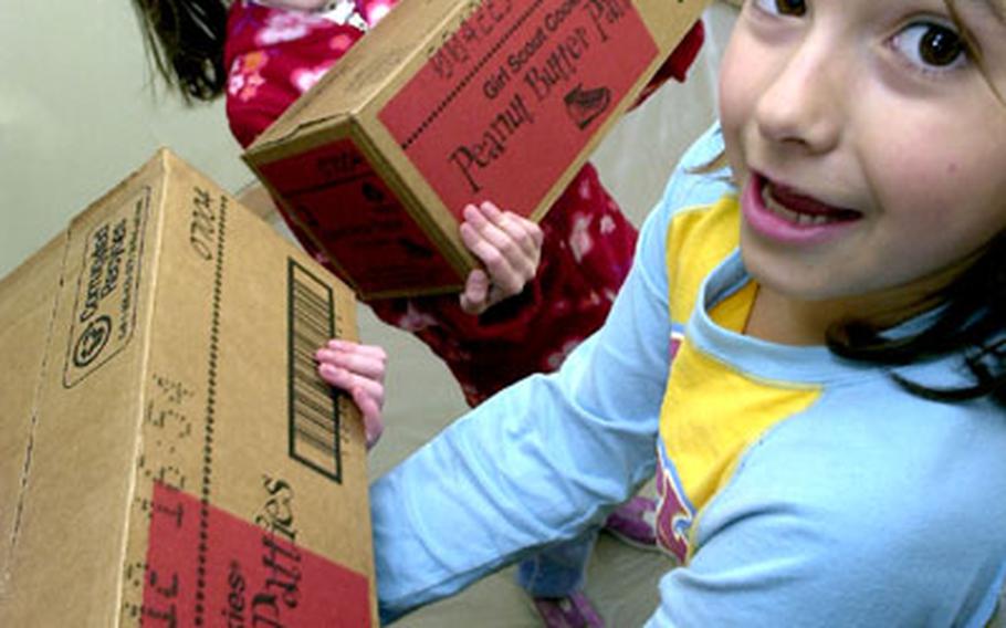 Stacy McCurdy, right, and Robyn Wells lug boxes of Girl Scout cookies into the group's building at Atsugi Naval Air Facility, Japan, on Tuesday.